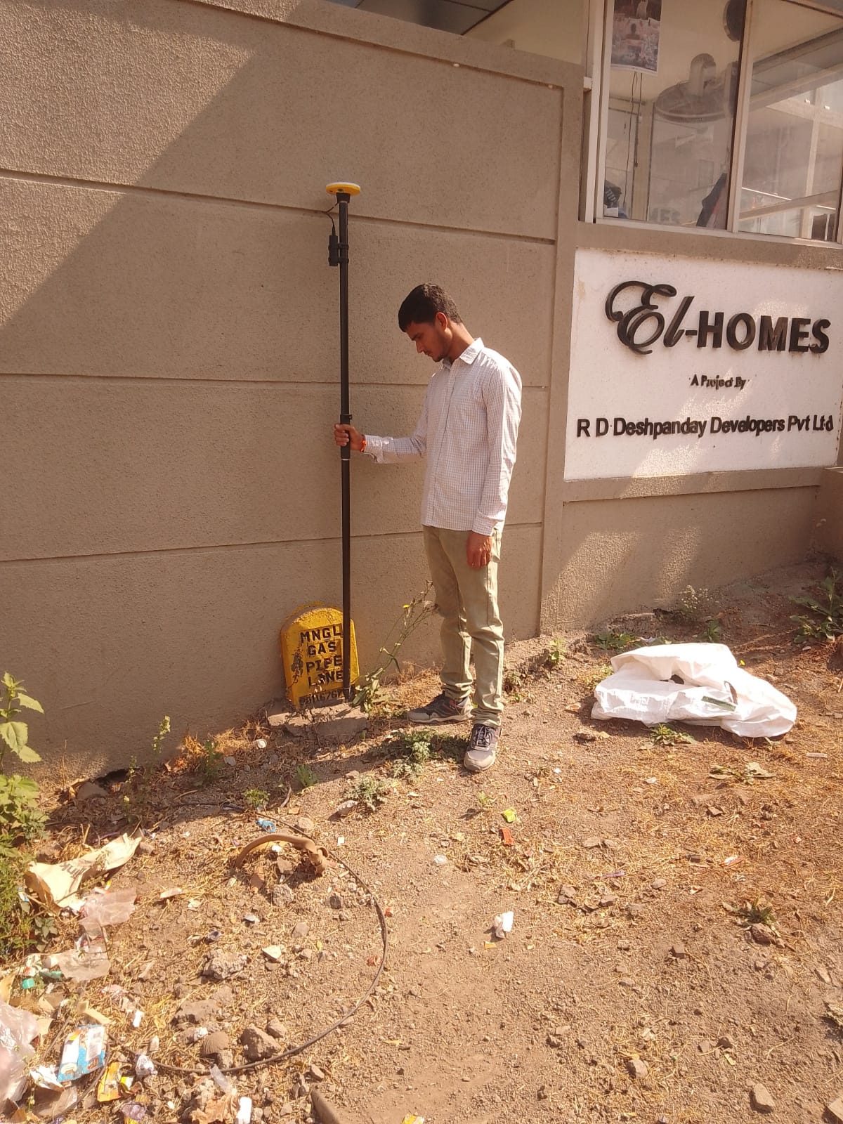 Surveyor with GNSS rover at a pipeline marker